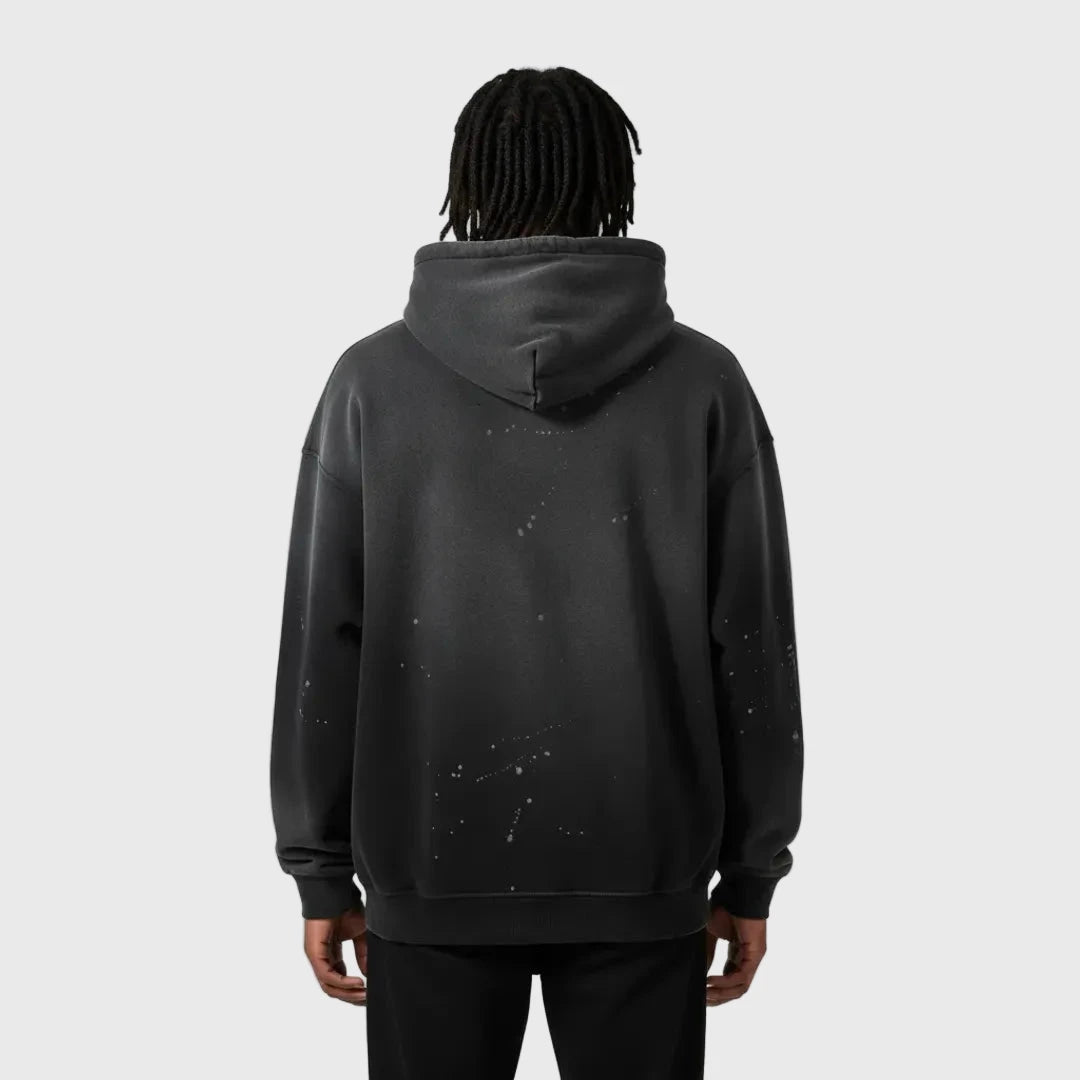 Person wearing a black MOD 1 hoodie with splatter design on the back against a gray background