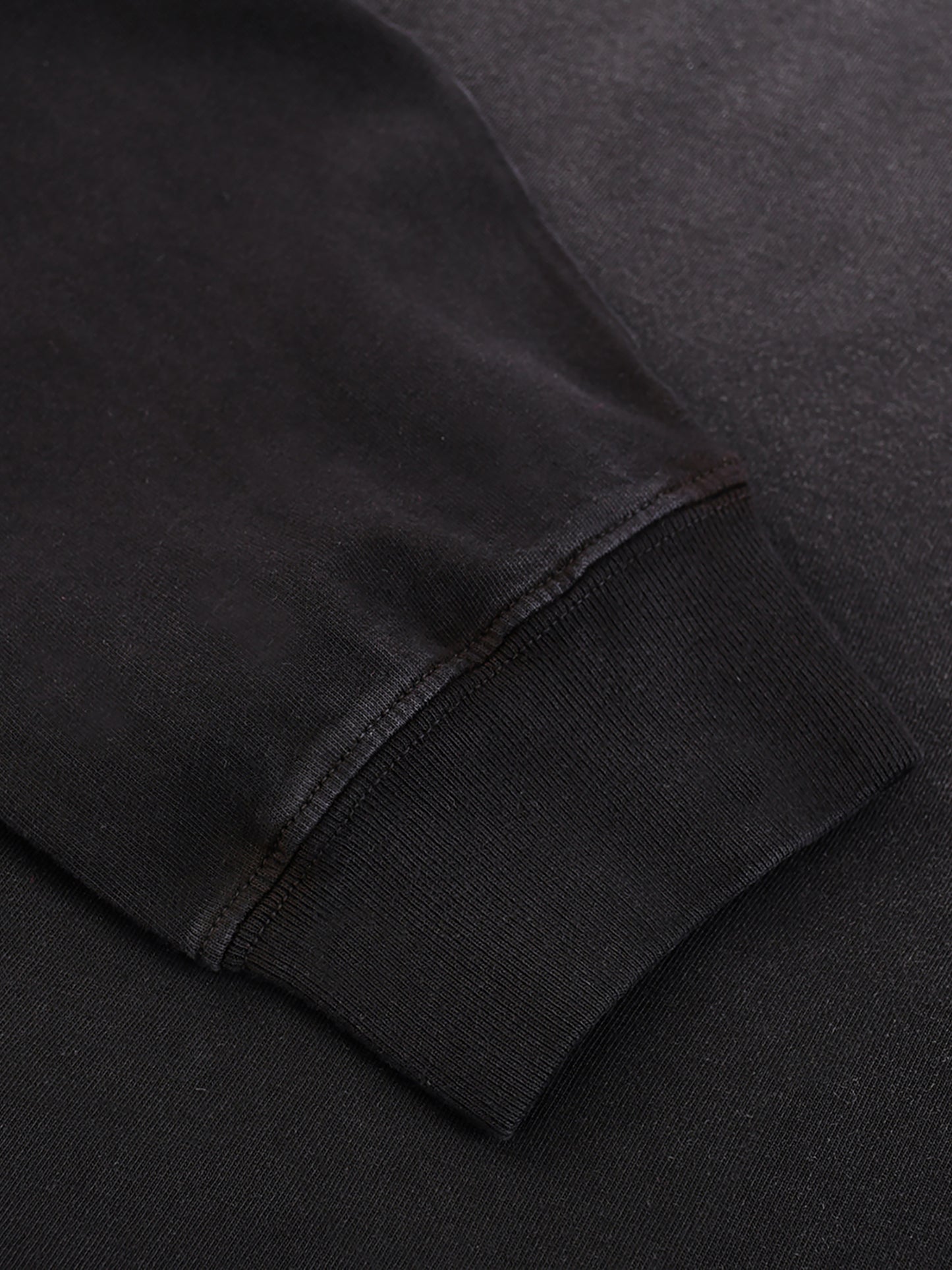 Close-up of a black sweatshirt sleeve on a dark background