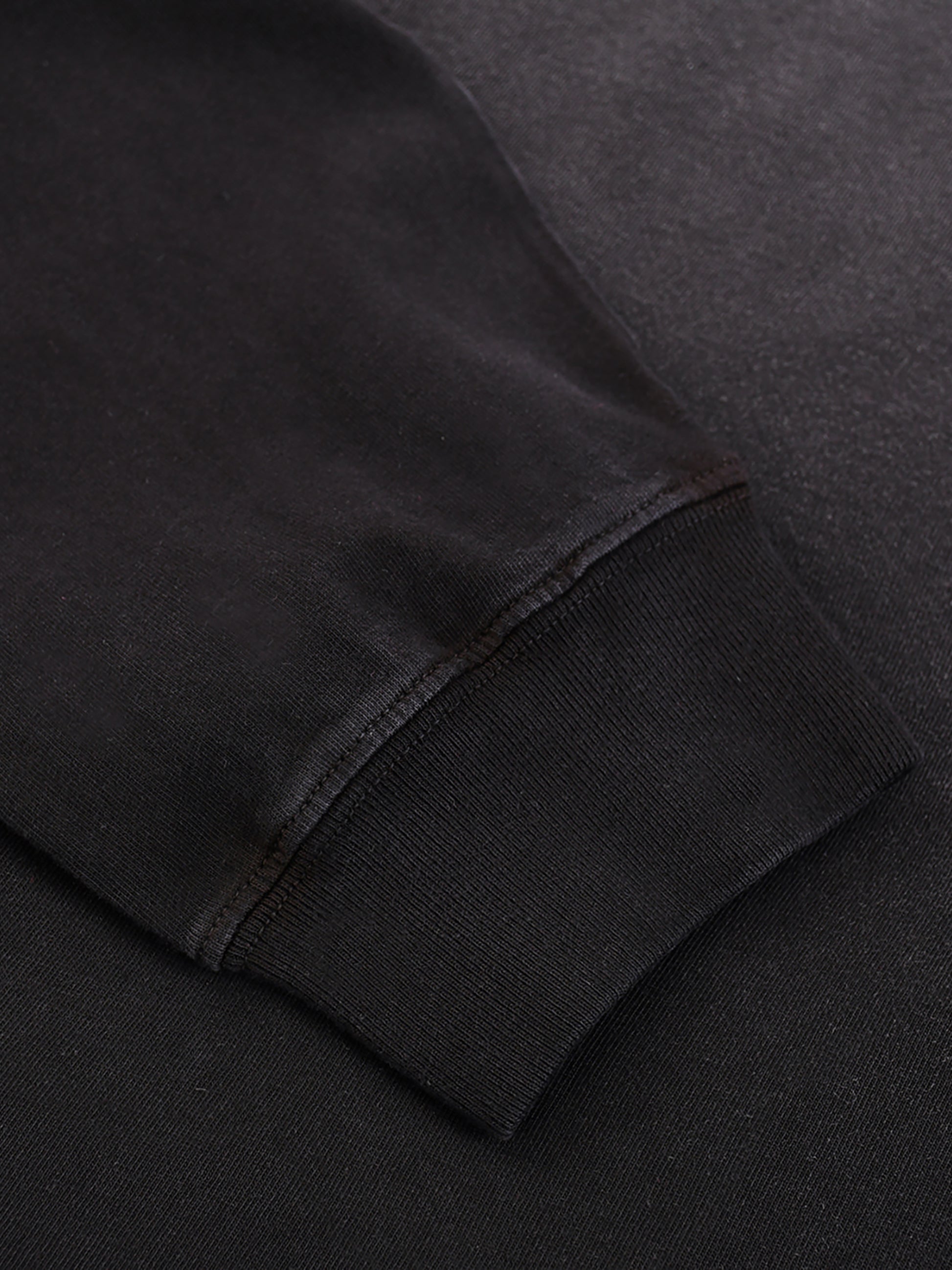 Close-up of a black sweatshirt sleeve on a dark background