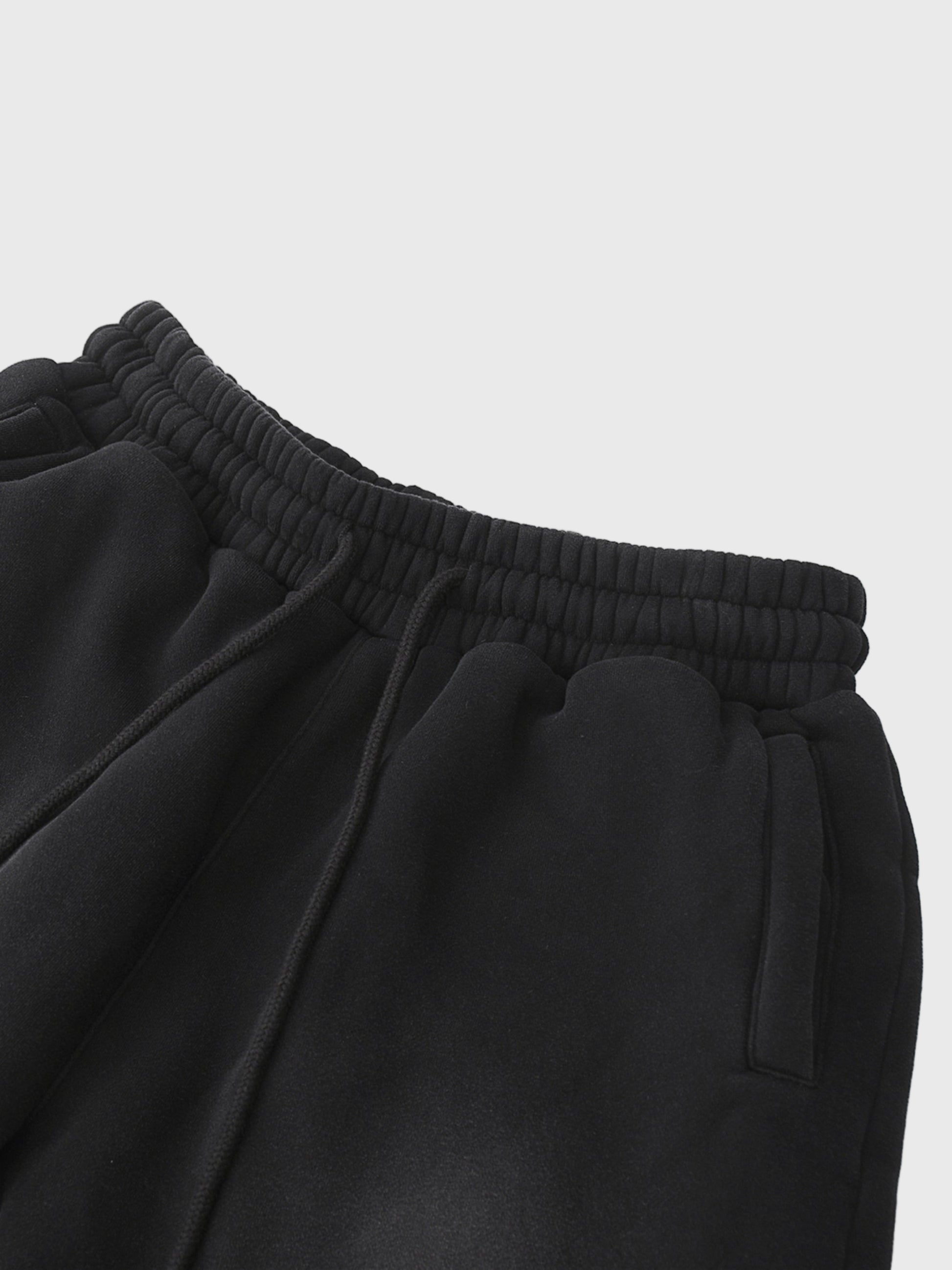 Close-up of black MOD 1 sweatpants with an elastic waistband on a light gray  background